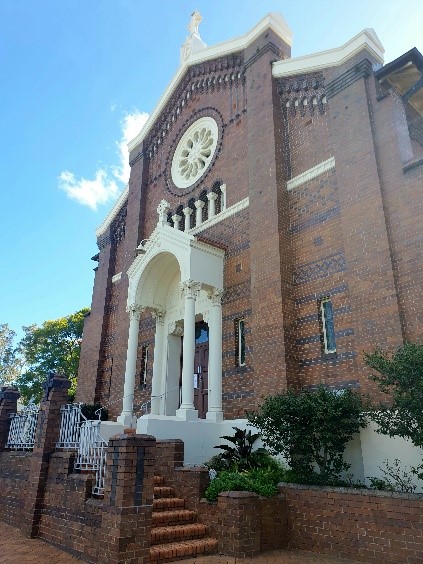Church exterior with brick façade and statue above the entrance