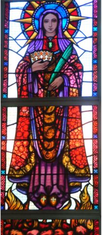 Stained glass artwork depicting a crowned female saint holding a heart and cross wearing a red and blue robe surrounded by star patterns