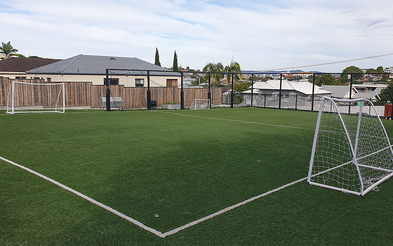 Fenced outdoor soccer field with goal posts and surrounding houses