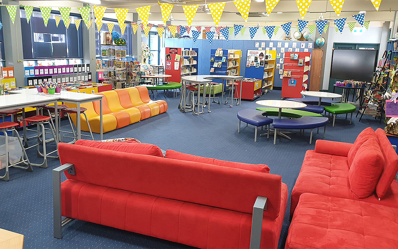 School library interior with study tables, shelves and reading areas