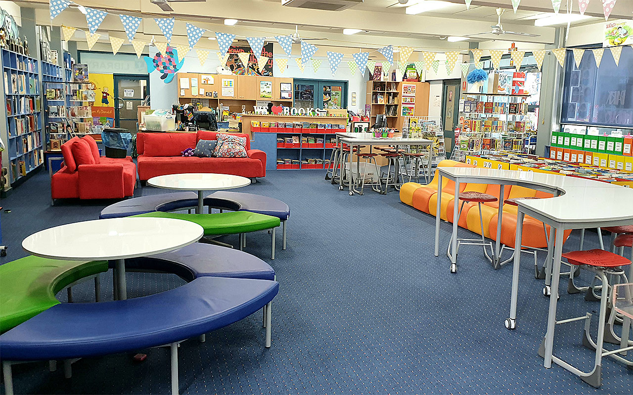 School library with bookshelves, tables, colourful seating and indoor learning spaces