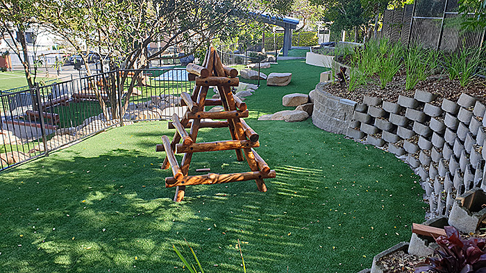 Timber climbing structure on a grassy outdoor play area