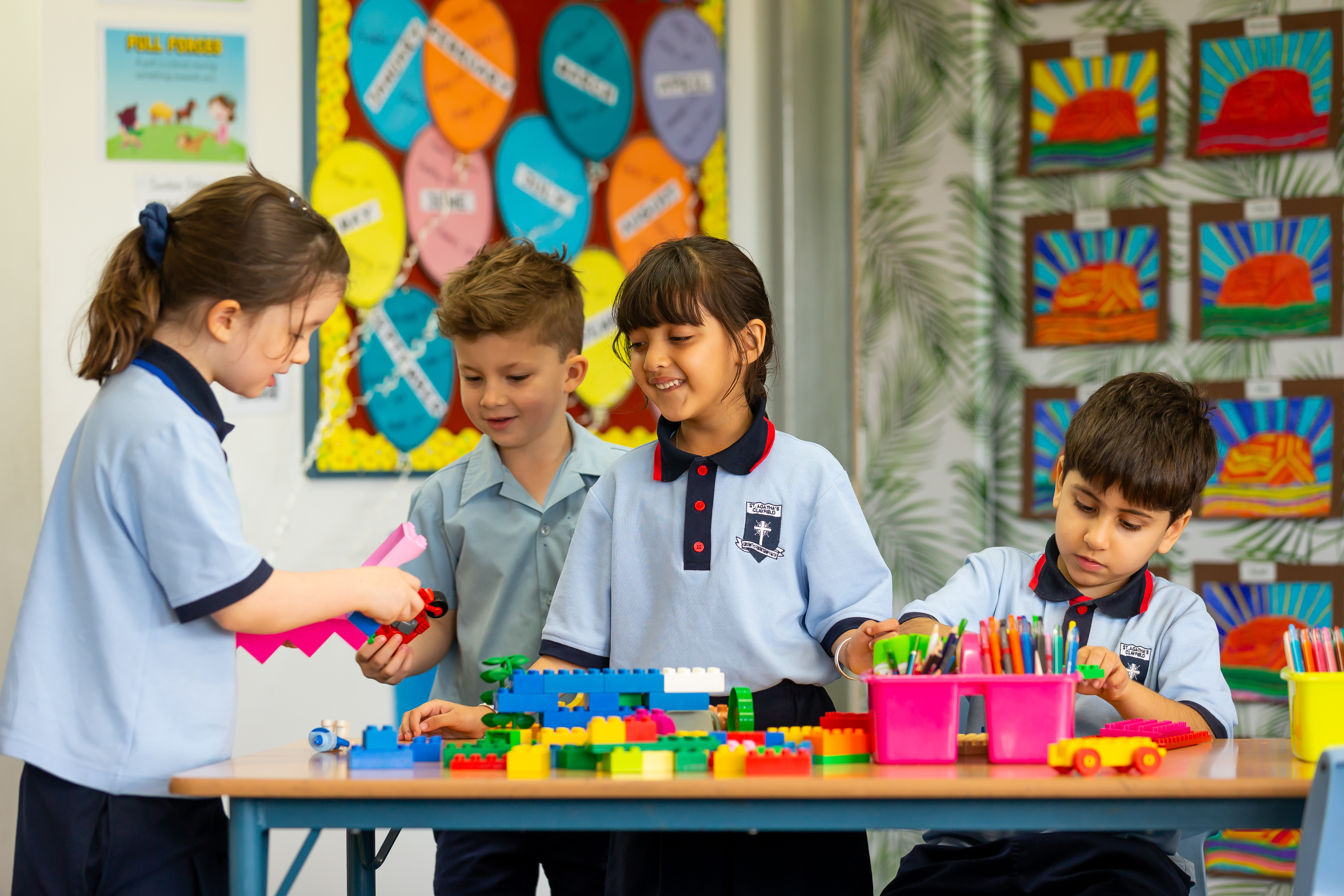 Students working together at a classroom table with building blocks, coloured pencils and creative materials