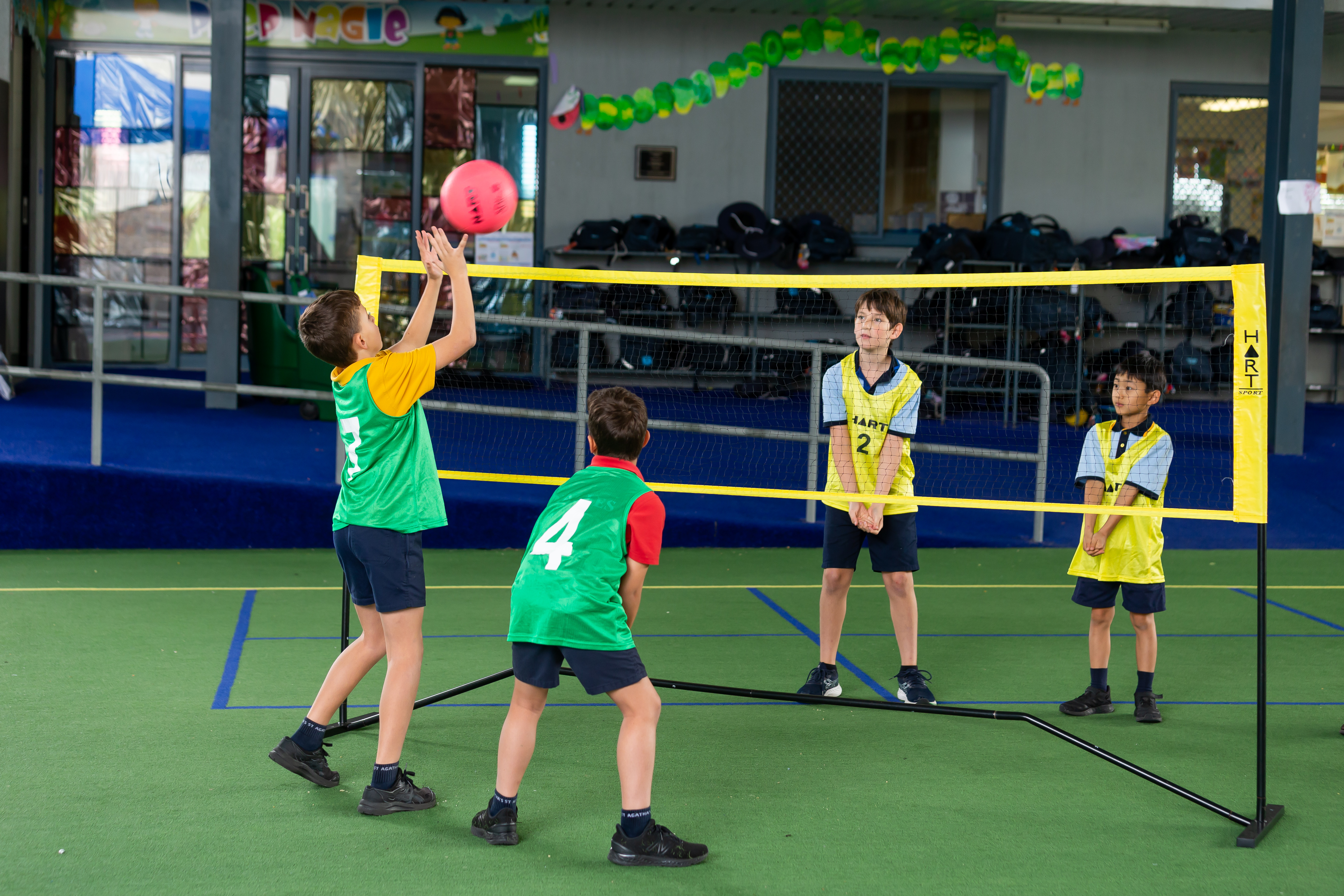 Students participating in a volleyball game during a physical education lesson in the school playground