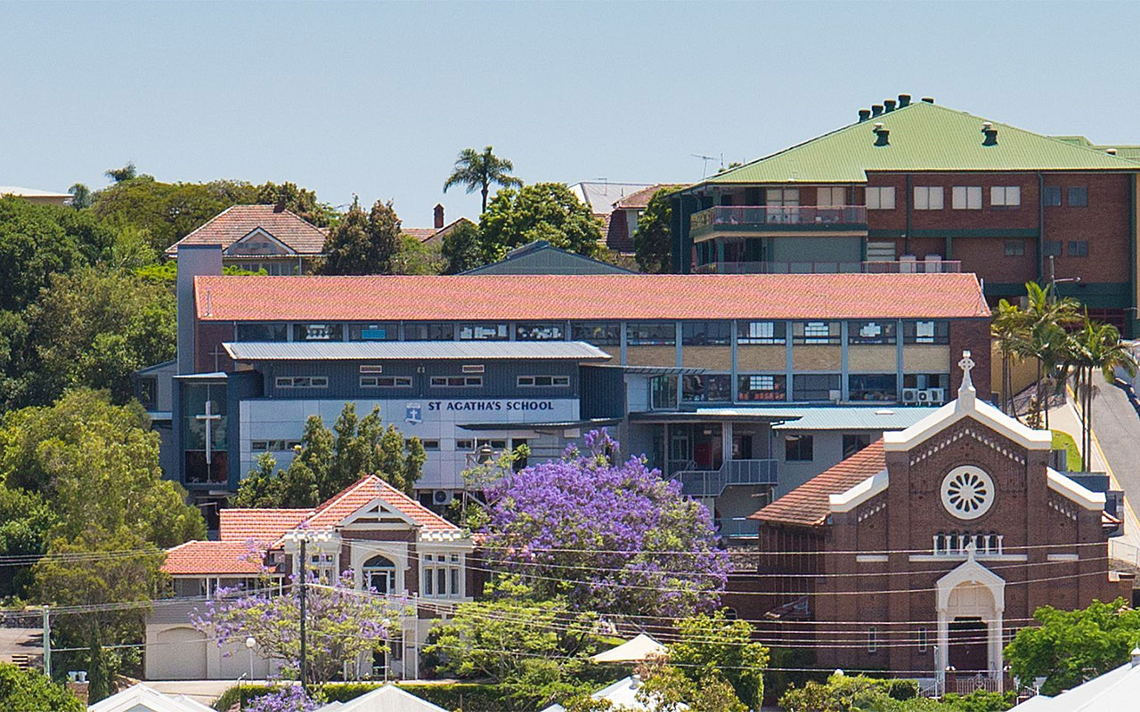 St Agatha’s Catholic Parish Primary School buildings viewed from a distance with trees and nearby church