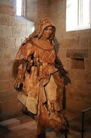 Stone statue of a robed figure holding objects inside a historic stone building