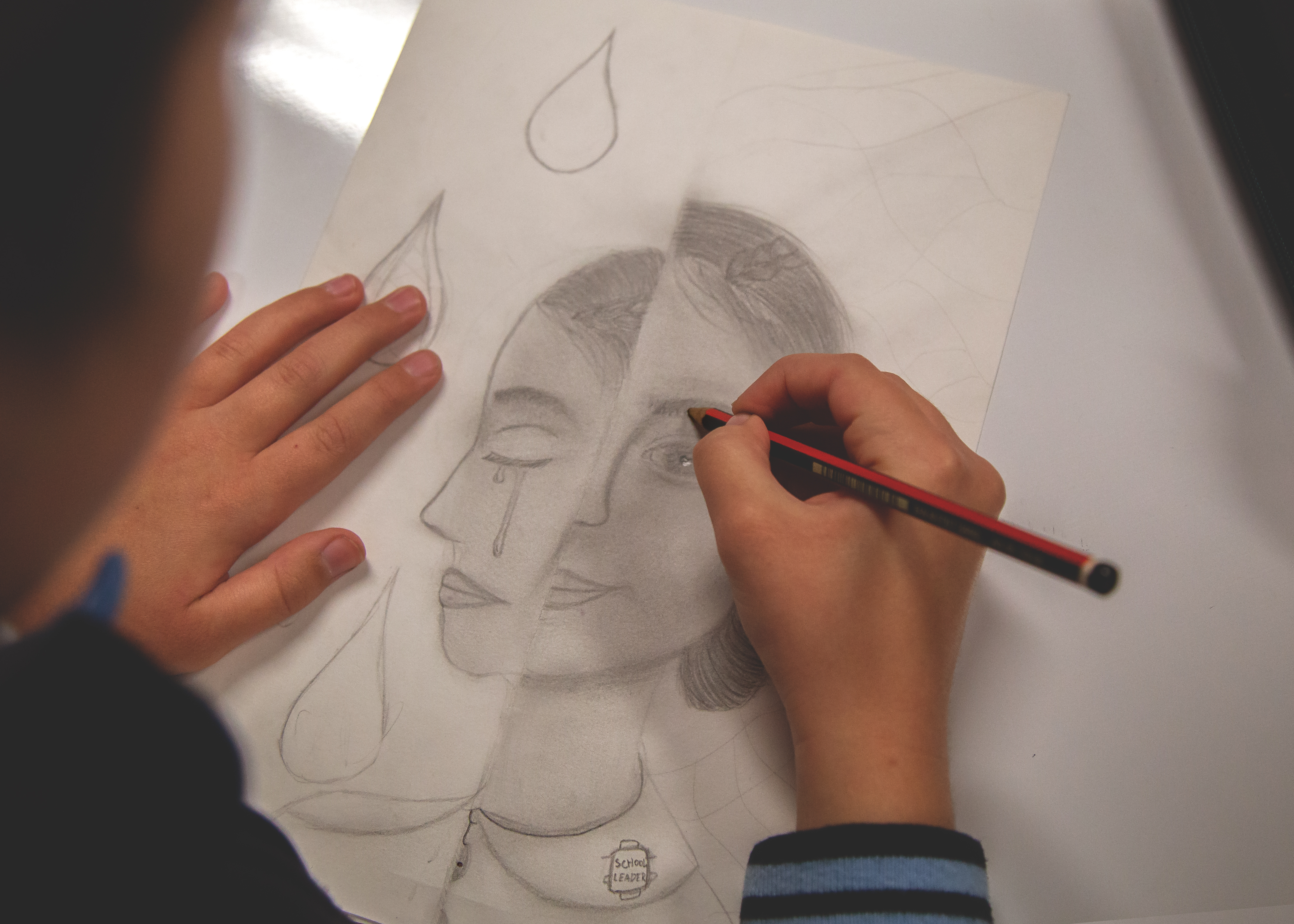 Student sketching a detailed pencil portrait during an art lesson